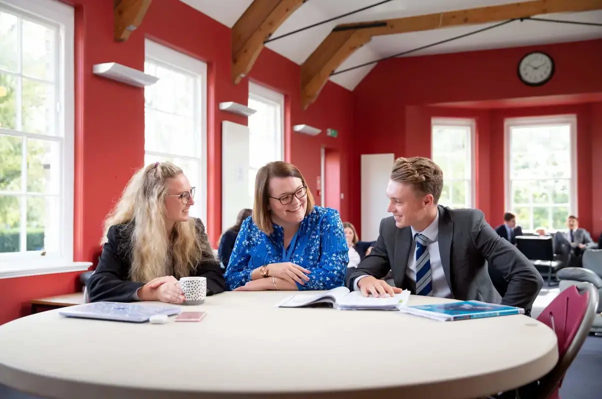 Sixth Form students at a table chatting with teacher